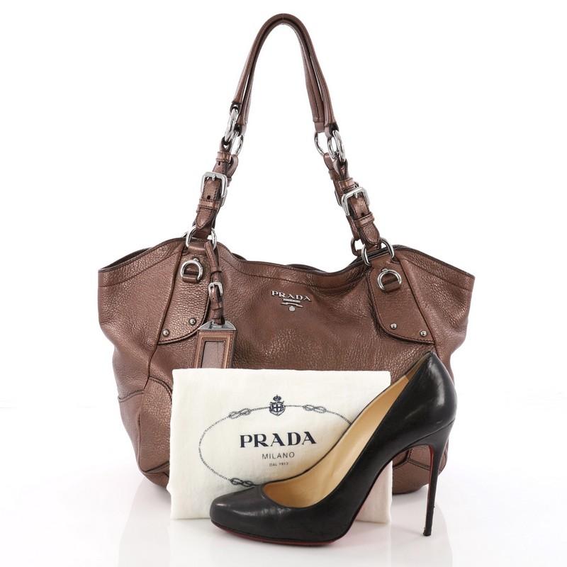 This authentic Prada Side Pocket Hobo Vitello Daino Medium is a sturdy and practical bag. Crafted from metallic brown vitello daino leather, this hobo features dual belted leather handles, two exterior side flat pockets, silver Prada Milano logo,