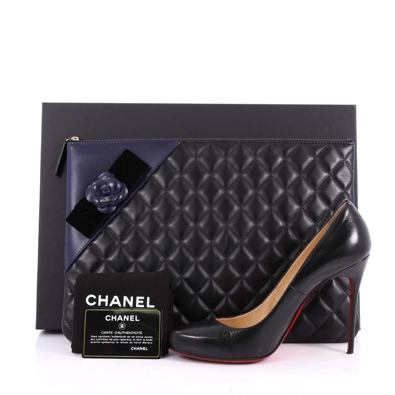 This authentic Chanel Camellia O Case Clutch Quilted Lambskin Large adds a touch of elegance to your everyday outfits. Crafted from black and white quilted lambskin, this chic clutch features a velvet bow with camelia flower detailing, tiny CC logo