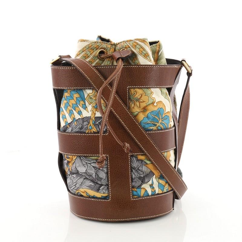 This authentic Salvatore Ferragamo Bucket Bag Leather and Quilted Printed Canvas Medium is an elegant and stylish bag made for modern fashionistas. Crafted from brown cut-out leather and quilted printed canvas, this chic bag features a leather