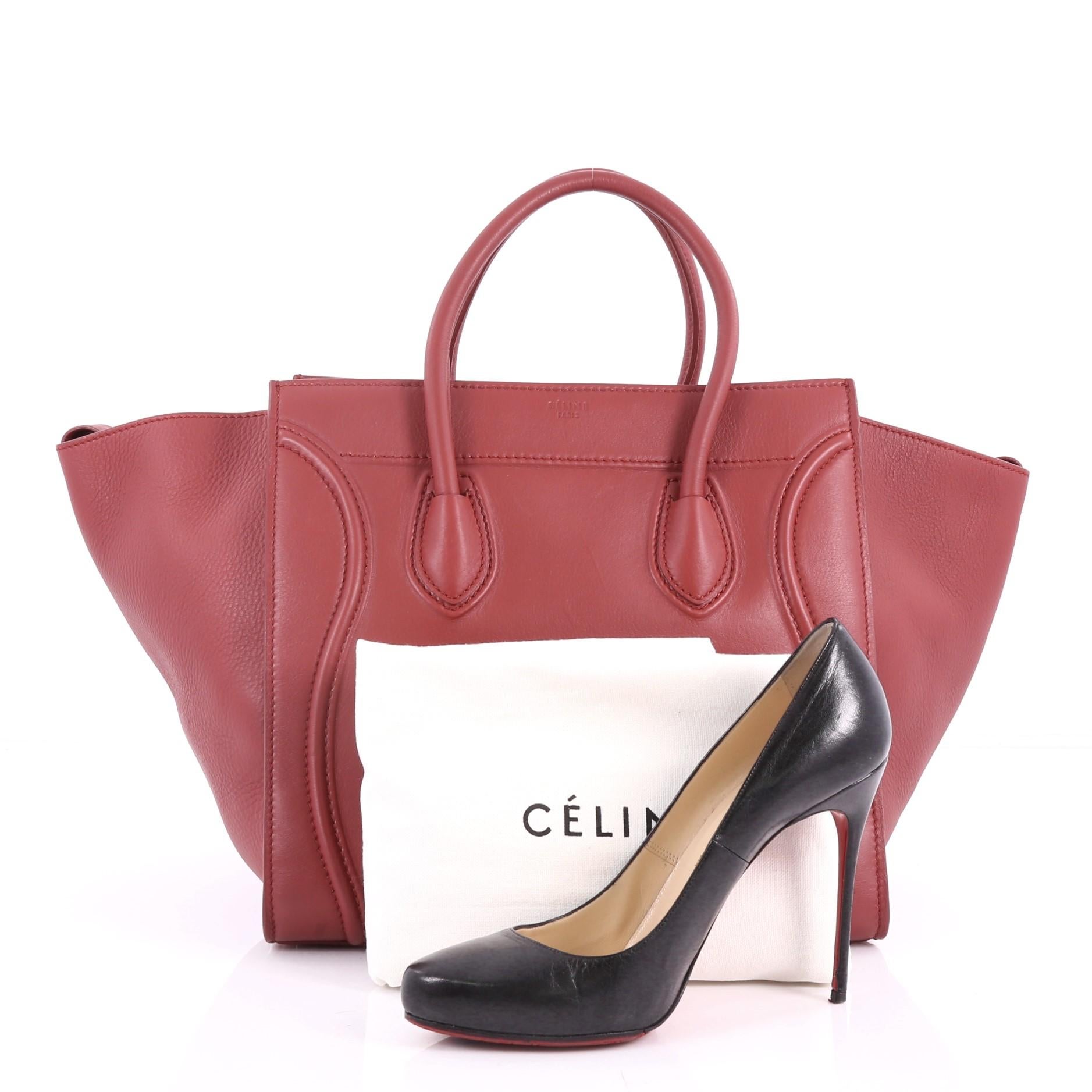 This authentic Celine Phantom Handbag Grainy Leather Medium is one of the most sought-after bags beloved by fashionistas. Crafted from red grainy leather, this minimalist tote features dual-rolled handles, an exterior front pocket, protective base
