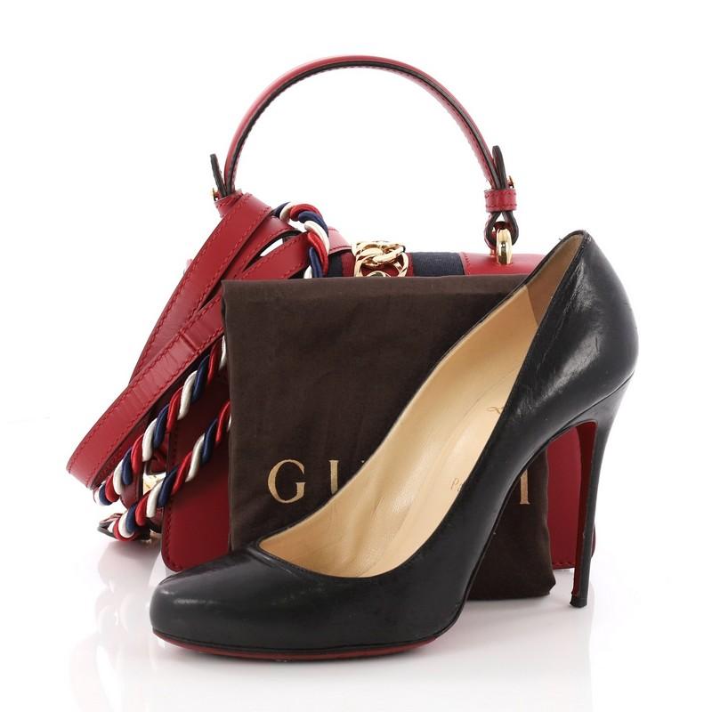 This authentic Gucci Sylvie Top Handle Bag Leather Mini is a stylish bag perfect for the modern fashionista. Crafted from red leather, this structured bag features a single looped leather handle, nylon web detail with curb chain and buckle closure,