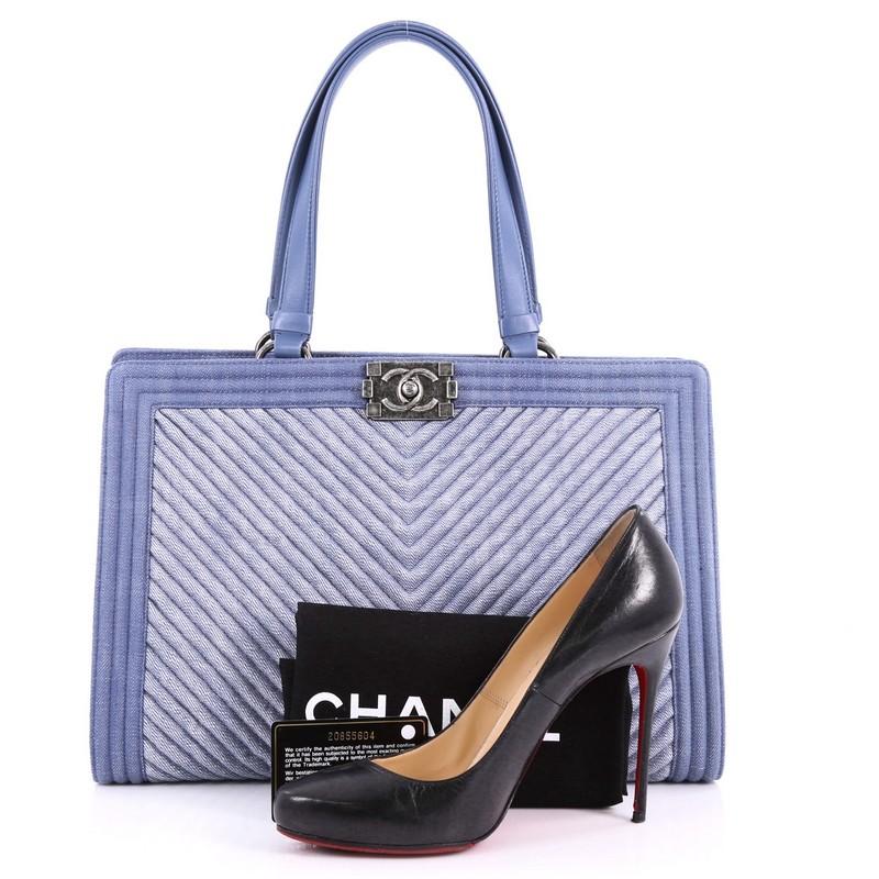 This authentic Chanel Boy Shopping Tote Chevron Denim combines classic Chanel craftsmanship with definitive style. Crafted from blue chevron denim, this rare tote features dual flat leather handles, subtle stitch detailing, protective base studs and