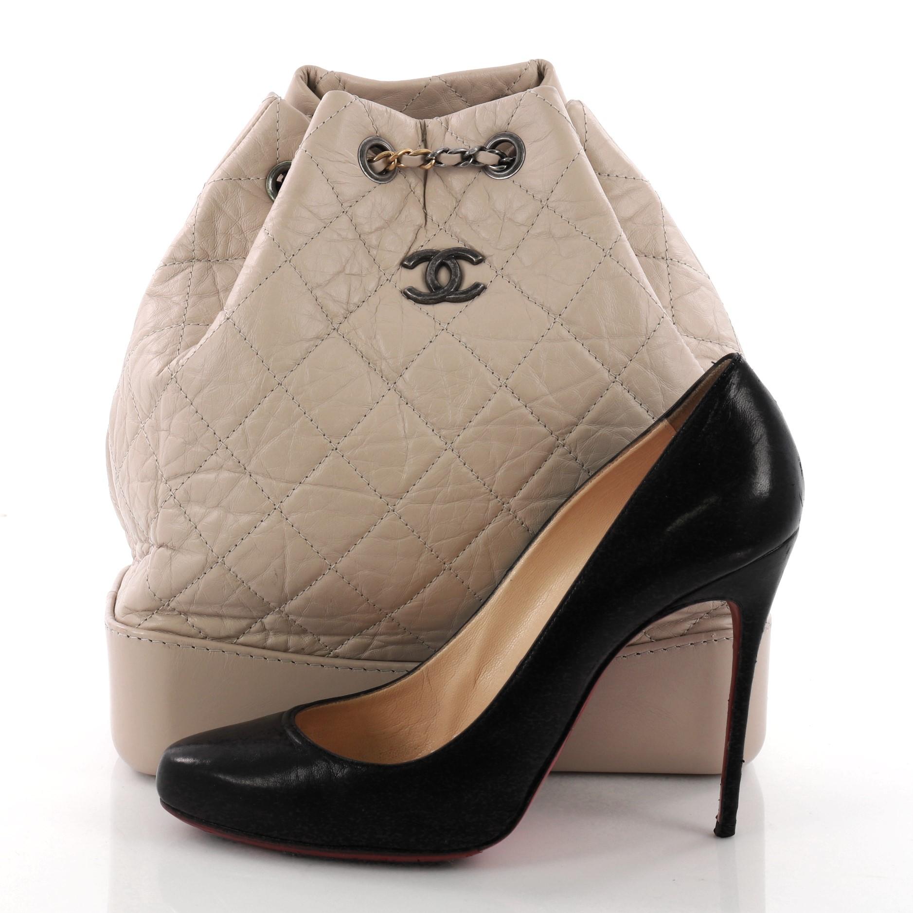 This authentic Chanel Gabrielle Backpack Quilted Aged Calfskin Medium displays a luxurious design with timeless modernity. Crafted from nude quilted aged calfskin leather, this chic backpack features gradient gold to aged silver woven-in leather