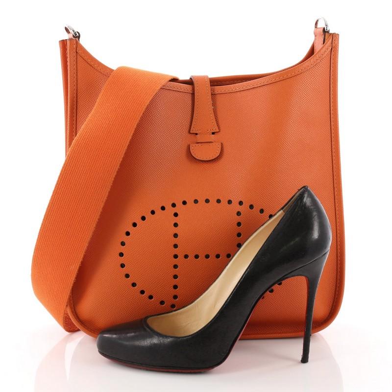 This authentic Hermes Evelyne Crossbody Gen I Epsom PM showcases a playful size perfect for daily, lightweight excursions. Crafted from classic orange epsom leather, this crossbody features a canvas strap, perforated H design at the front, and