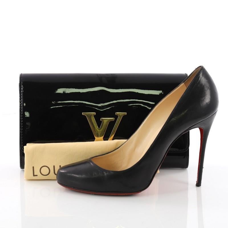 This authentic Louis Vuitton Louise Clutch Patent East West is a perfect choice of accessory for both day and evening looks. Crafted from black patent leather, this modern yet feminine clutch features oversized LV logo flip lock clasp in sleek