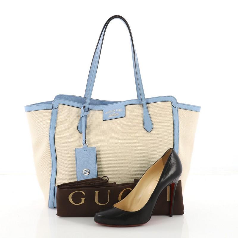 This authentic Gucci Swing Tote Canvas and Leather Medium is modern and sophisticated in design. Crafted in light blue leather and beige canvas, this elegant tote features tall dual-slim handles, expanded wing silhouette, and gold-tone hardware