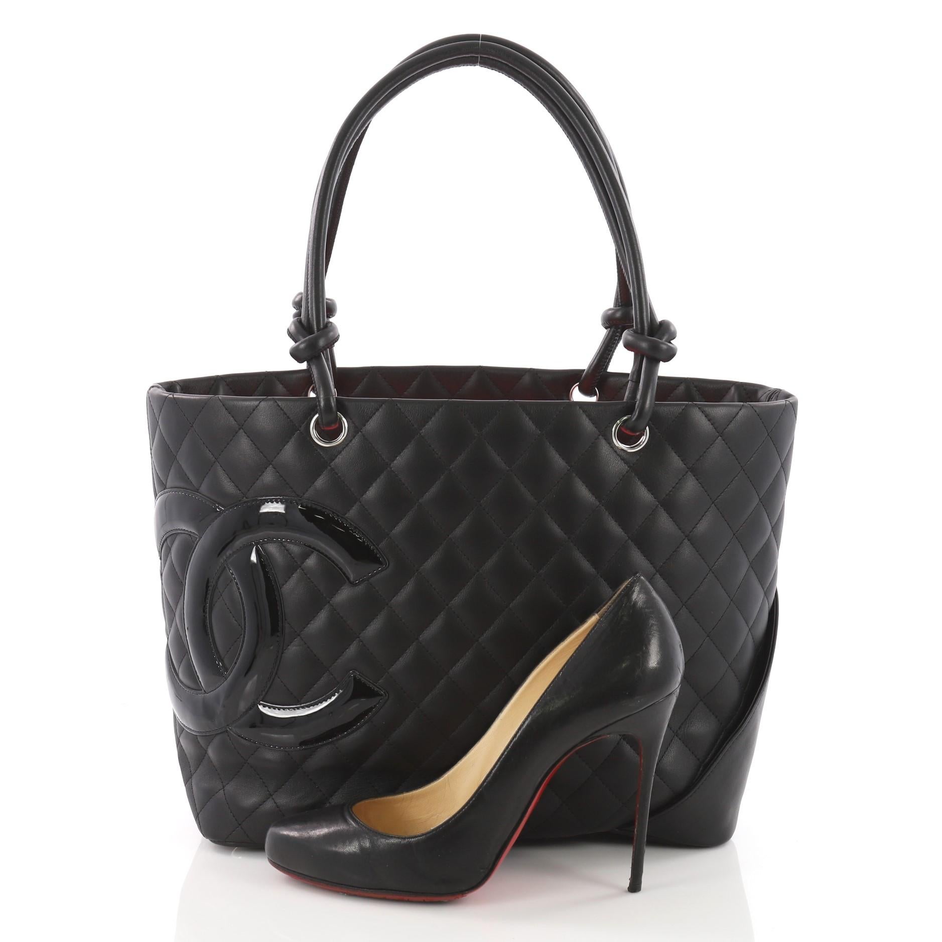 This authentic Chanel Cambon Tote Quilted Leather Large is a finely crafted bag from the brand's Cambon Collection. Designed from black diamond quilted leather, this tote displays a large black patent leather interlocking CC side logo, dual-rolled