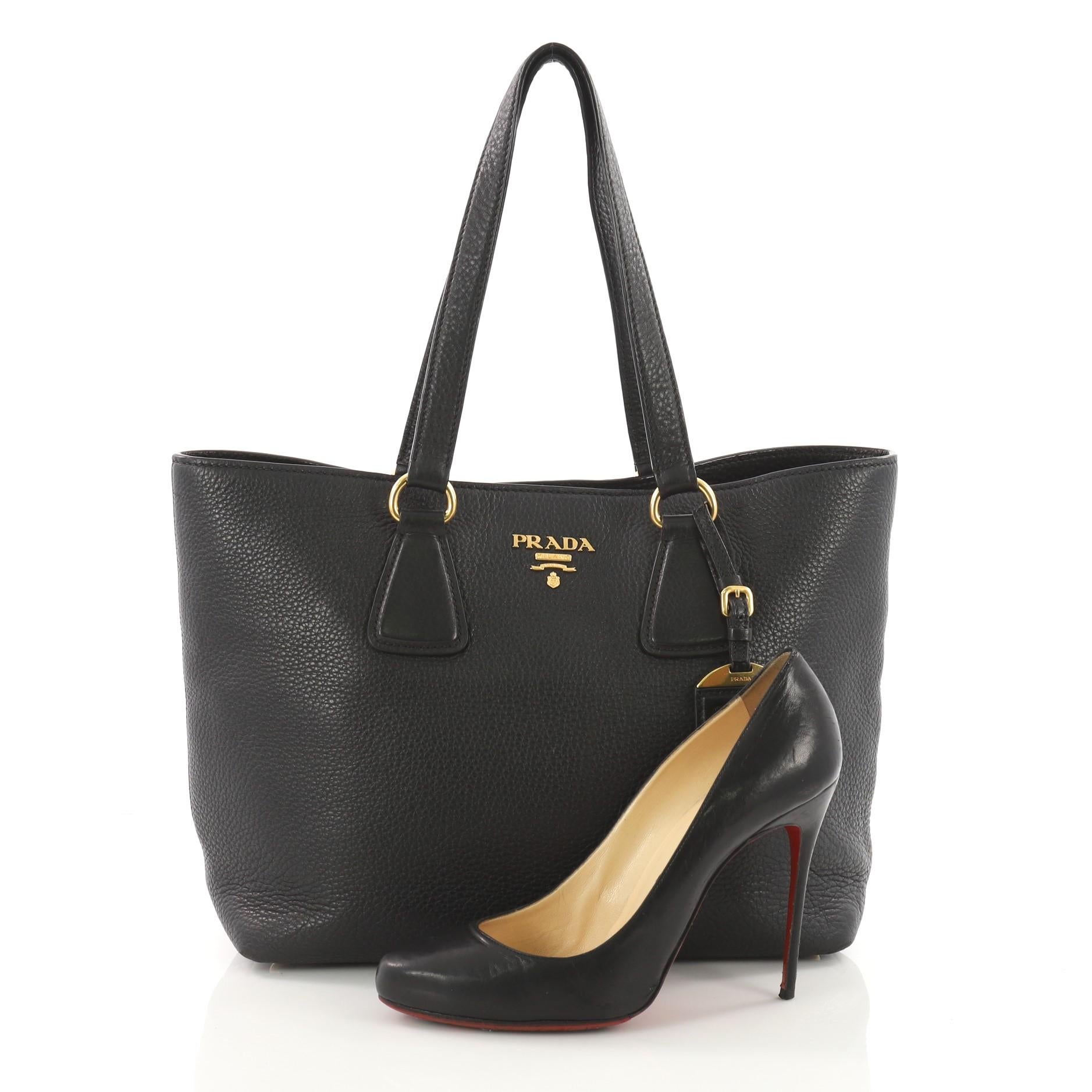 This authentic Prada Open Tote Vitello Daino Small is a chic and stylish everyday bag for casual looks. Crafted from black vitello daino leather, this simple and functional tote features dual-flat leather handles, signature Prada logo, and gold-tone