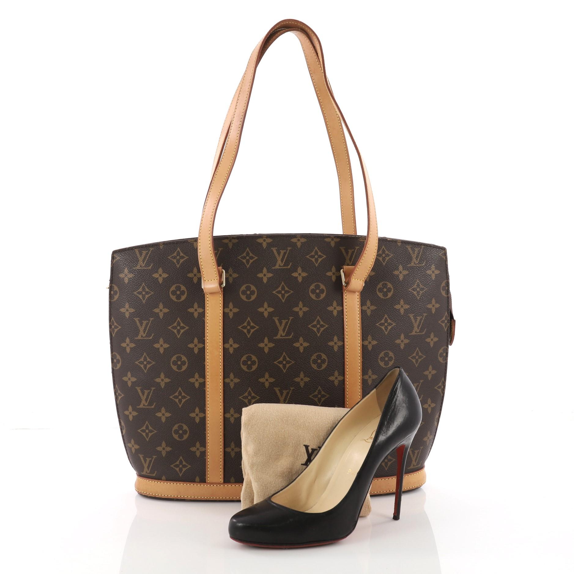 This authentic Louis Vuitton Babylone Handbag Monogram Canvas is a stylish and durable tote ideal for everyday use. Crafted from brown monogram coated canvas, this bag features natural vachetta cowhide leather straps and trims, gold-tone hardware