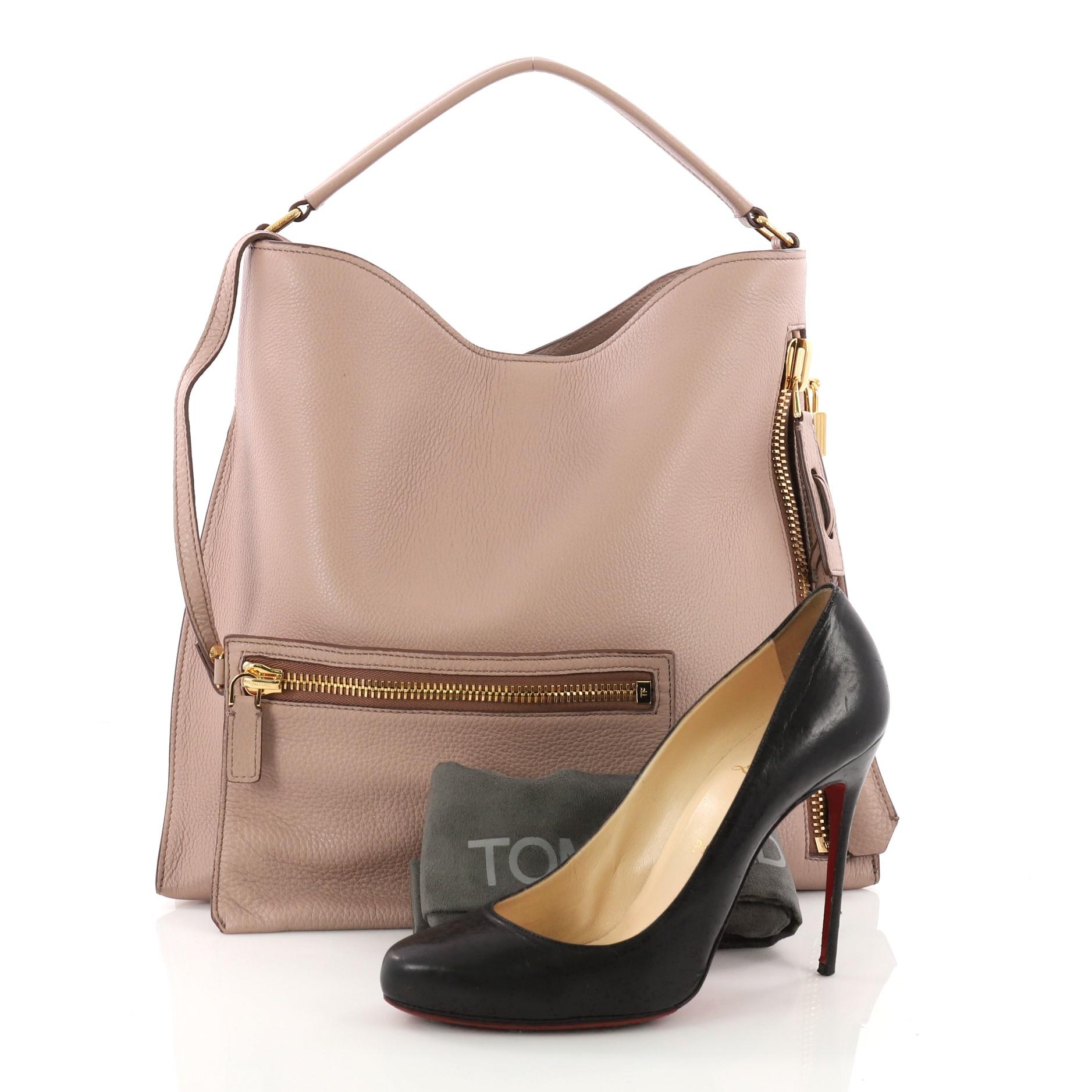 This authentic Tom Ford Alix Hobo Leather Small showcases a minimalist, clean and functional accessory perfect for the modern woman. Constructed in rose leather, this tote features a looping top handle, exterior zip pocket, padlock on pull tab, and