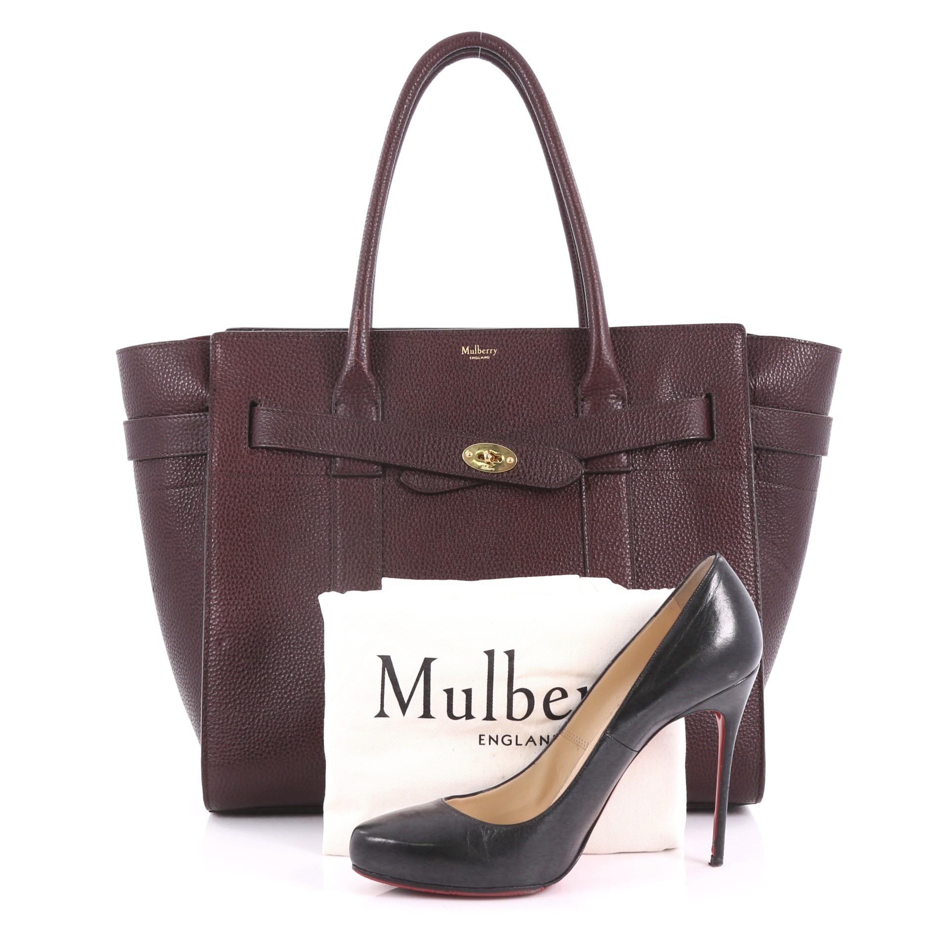 This Mulberry Bayswater Zipped Tote Leather Medium, crafted in maroon leather, features dual-rolled leather handles, belted leather straps with miniature Postman’s lock and gold-tone hardware. Its zip closure opens to a maroon-suede-lined interior