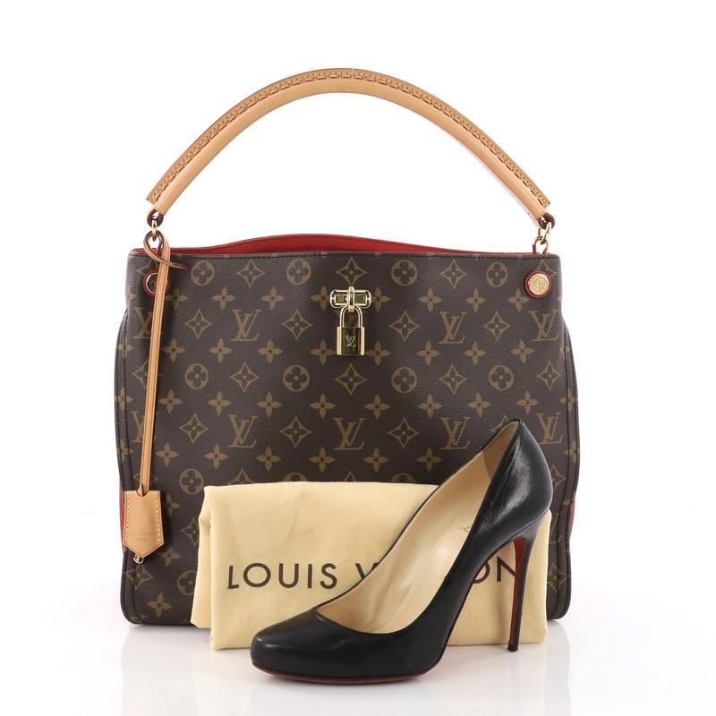 This Louis Vuitton Gaia Handbag Monogram Canvas, crafted from brown monogram coated canvas, features natural cowhide rolled leather handle, red leather side gussets, and gold-tone hardware accents. Its wide open top showcases a red microfiber-lined