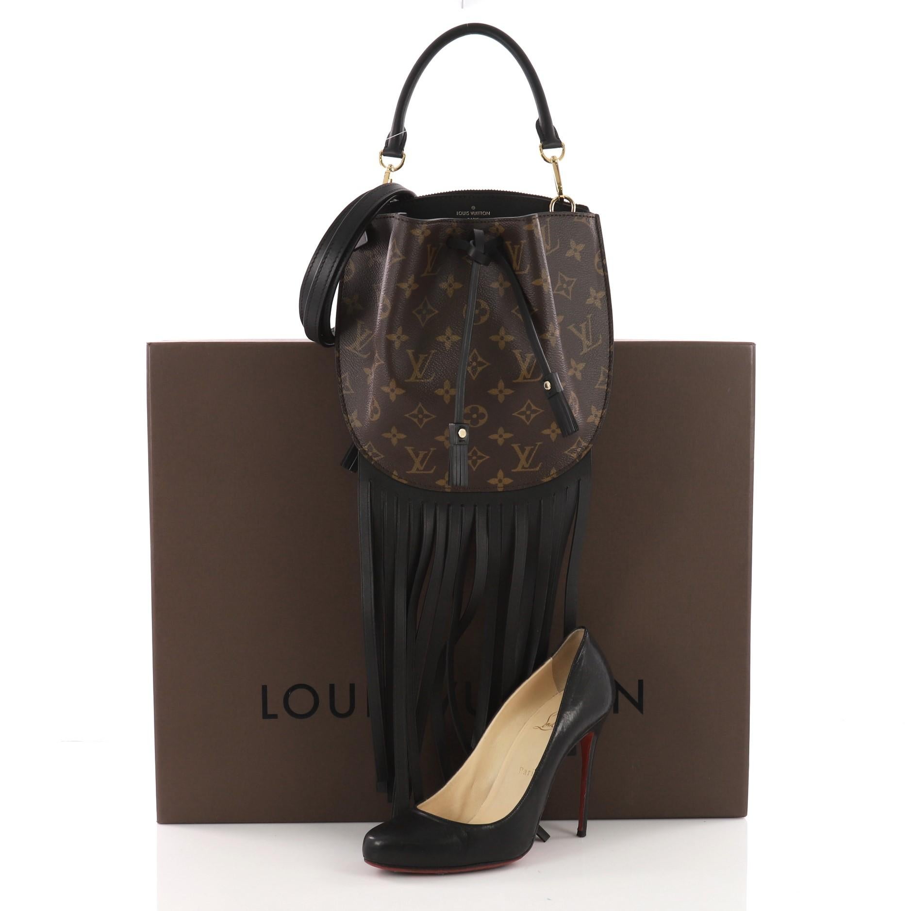This Louis Vuitton Fringed Noe Monogram Canvas with Leather, crafted in brown monogram coated canvas, features cascading black leather fringe, supple pleated construction, and gold-tone hardware. Its drawstring closure opens to a black microfiber