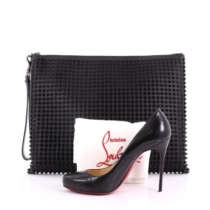 This Christian Louboutin Peter Pouch Spiked Leather Medium, crafted from black spiked leather, features a wristlet strap, exterior back zip pocket, and gunmetal-tone hardware. Its zip closure opens to a red fabric interior with multiple card slots