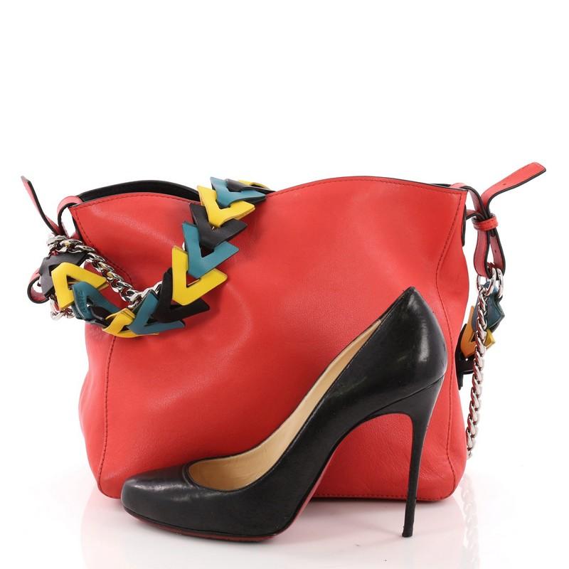 This Loewe V Bucket Bag Leather, crafted from red leather, features chain-link and leather strap, tri-tone leather strap and silver-tone hardware. Its magnetic closure opens to a beige fabric interior with slip pocket. **Note: Shoe photographed is
