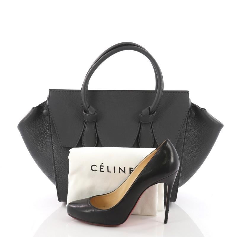 This Celine Tie Knot Tote Grainy Leather Small, crafted from grey grainy leather, features dual-rolled leather handles with signature knot accents, expandable wings and gold-tone hardware. It opens to a grey suede interior with side zip and slip