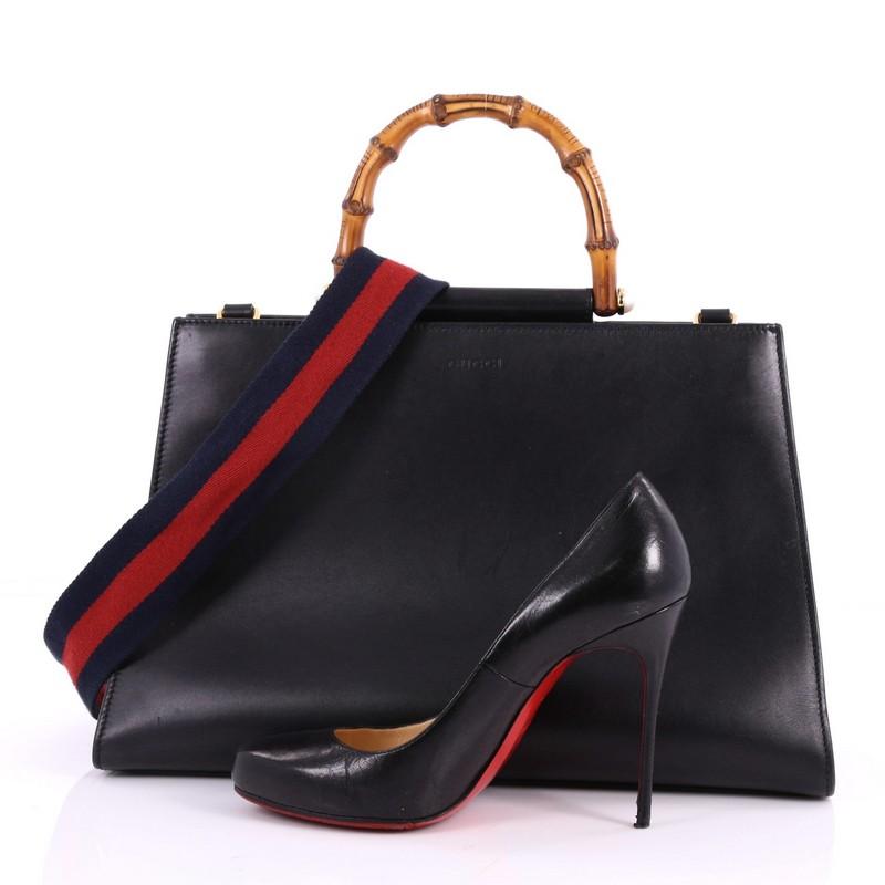 This authentic Gucci Nymphaea Top Handle Bag Leather Medium from 2017 is a stylish bag perfect for the modern fashionista. Crafted in black leather, this gorgeous bag features a blue and red nylon Web shoulder strap, bamboo handle with pearls and