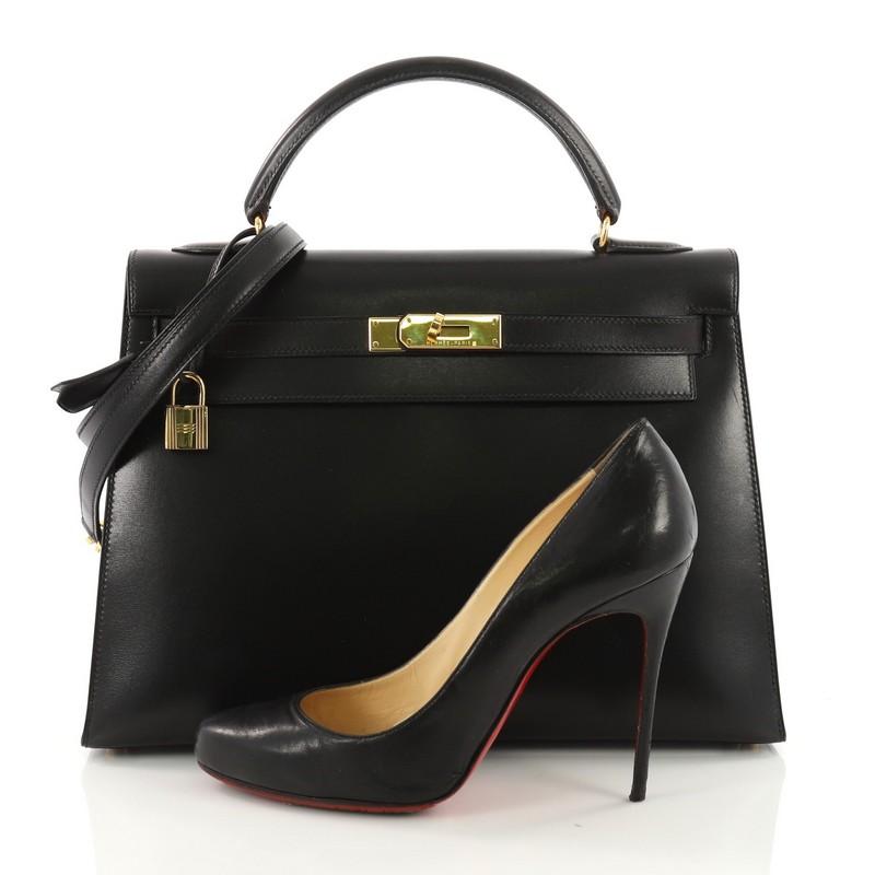 This Hermes Kelly Handbag Black Box Calf with Gold Hardware 32, crafted black box calf leather, features single rolled top handle, a frontal flap, and gold-tone hardware. Its turn lock closure opens to a black leather interior with zip pocket. Date