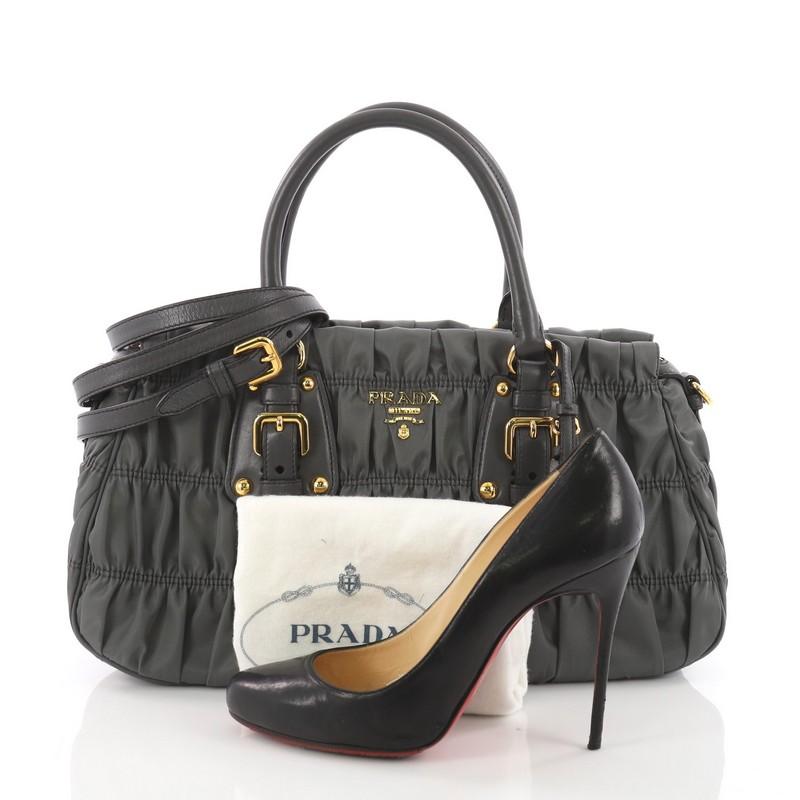 This Prada Gaufre Convertible Satchel Tessuto Medium, crafted from grey tessuto fabric, features dual-rolled leather handles, raised Prada logo, and gold-tone hardware. Its zip closure opens to a gray fabric interior with side zip and slip pocket.