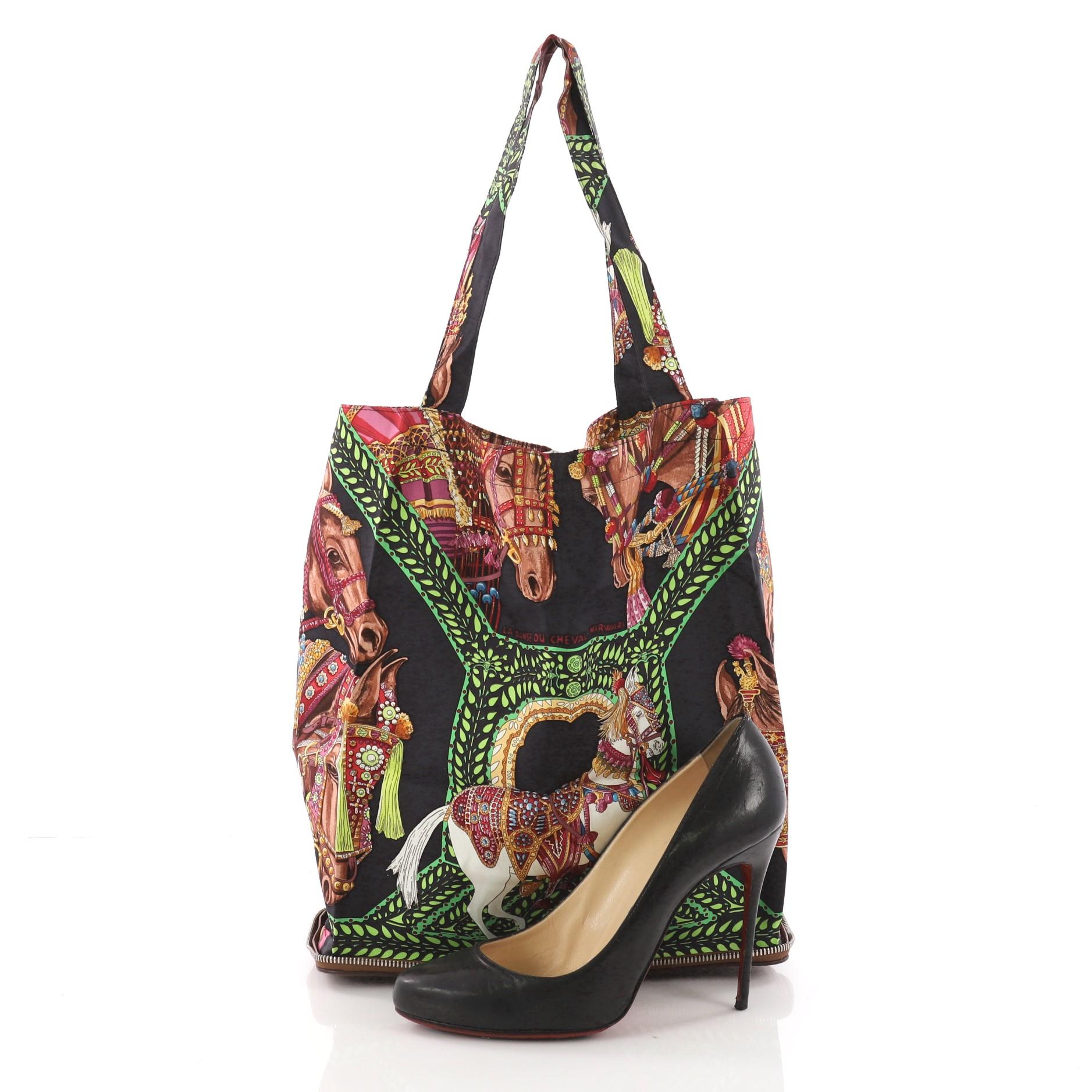 This Hermes Silky Pop Tote Printed Silk, crafted from multicolor danse du cheval marwari printed silk and brown leather, features dual silk handles, a leather casing that serves as the base of the bag and palladium-tone hardware. It opens to a green