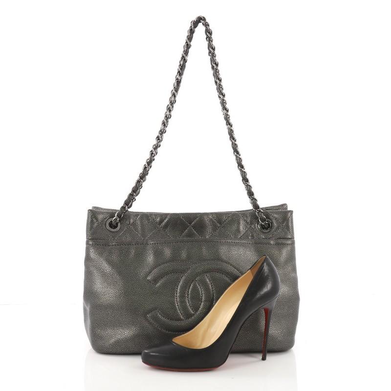 This Chanel Timeless CC Soft Tote Caviar Medium, crafted in pewter caviar leather, features woven in leather chain link straps, exterior front and back slip pockets, and silver-tone hardware. Its magnetic snap closure opens to a black fabric