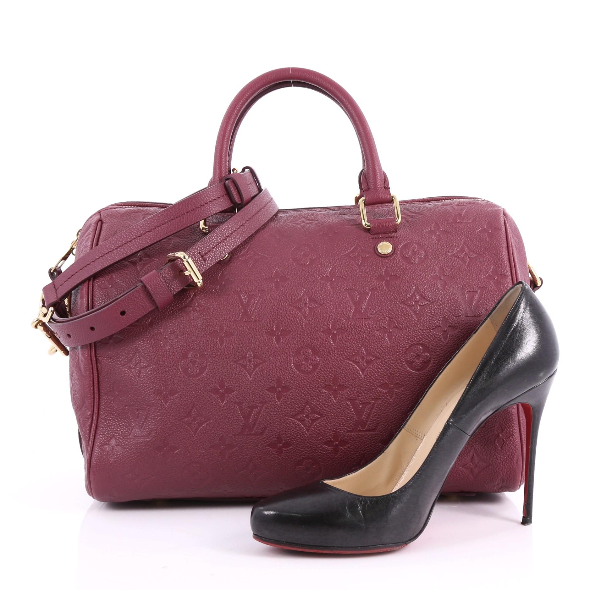 This Louis Vuitton Speedy Bandouliere Bag Monogram Empreinte Leather 30, crafted in plum monogram empreinte leather, features dual rolled leather handles, protective base studs and gold-tone hardware. Its two-way zip closure opens to a plum fabric