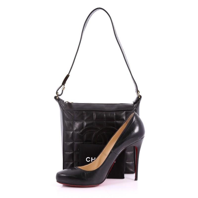 This Chanel Chocolate Bar CC Shoulder Bag Quilted Leather Small, crafted in black leather, features long leather shoulder strap, square quilt design, and gold-tone hardware. Its zip closure opens to a black fabric interior with zip and slip pockets.