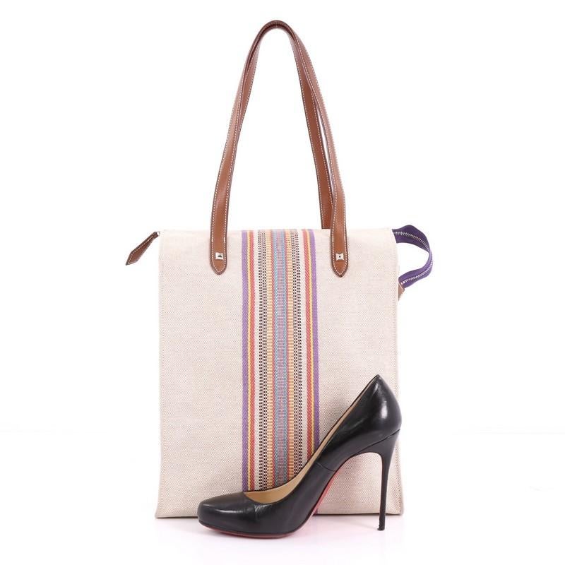 This Hermes Mira Ganges Tote Rainbow Toile Tall, crafted from a rainbow and beige toile, features dual flat leather handles, and palladium-tone hardware. Its zip closure opens to a rainbow and beige toile interior. Date stamp reads: L square (2008).