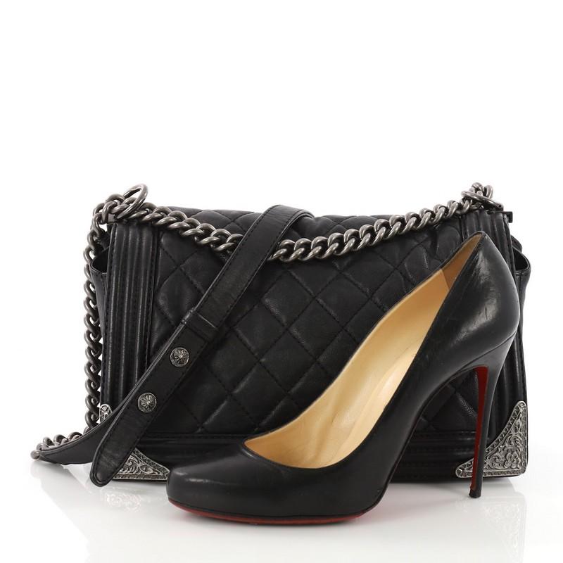 This Chanel Paris-Dallas Compartment Boy Flap Bag Quilted Calfskin with Metal Adornments New Medium, crafted from black quilted calfskin leather, features a chunky chain-link strap with leather pad, gorgeous metal adornments on both corner edges and