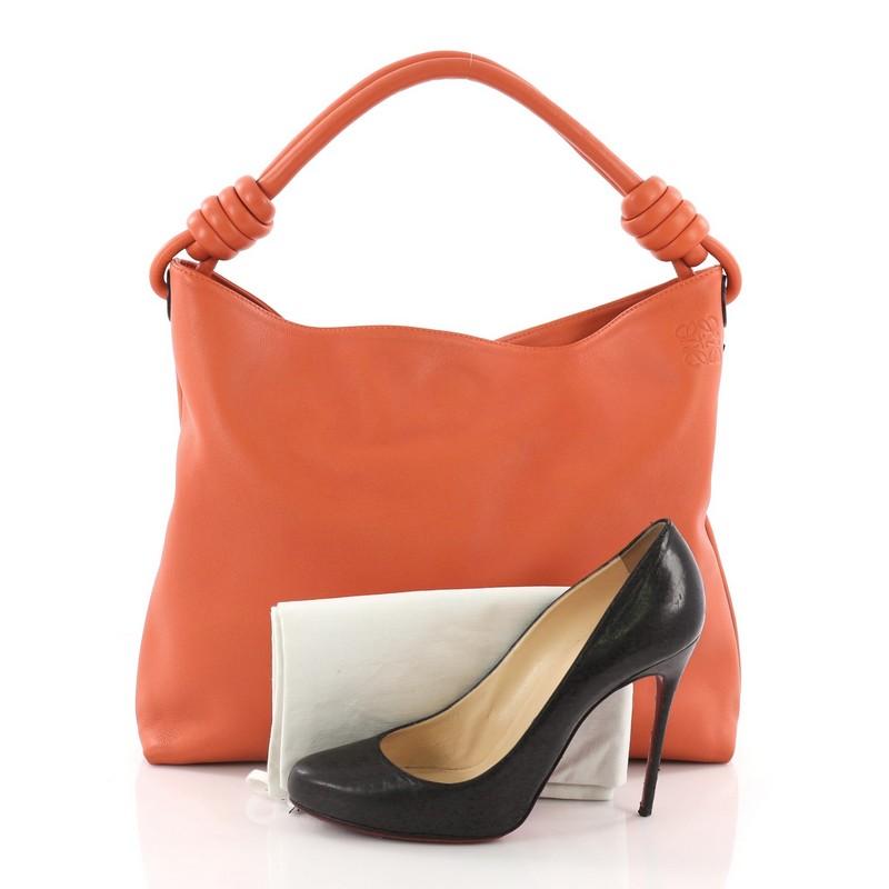 This Loewe Flamenco Knot Hobo Leather, crafted from orange leather, features a looping leather handles with knotted ends and silver-tone hardware. It opens to a beige fabric interior with zip and slip pockets. **Note: Shoe photographed is used as a
