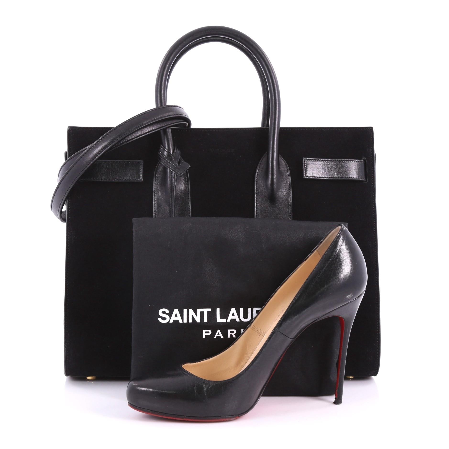 This Saint Laurent Sac de Jour NM Handbag Suede Small, crafted from black suede, features dual-rolled leather handles, protective base studs, and gold-tone hardware accents. Its leather tabs open to a black leather interior. **Note: Shoe