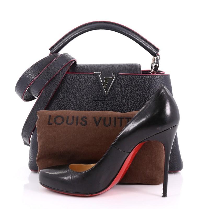 This Louis Vuitton Capucines Handbag Leather BB, crafted from black leather, features a single rolled leather handle, frontal flap with the classic monogram flower, and silver-tone hardware accents. Its flap opens to a pink leather interior with two