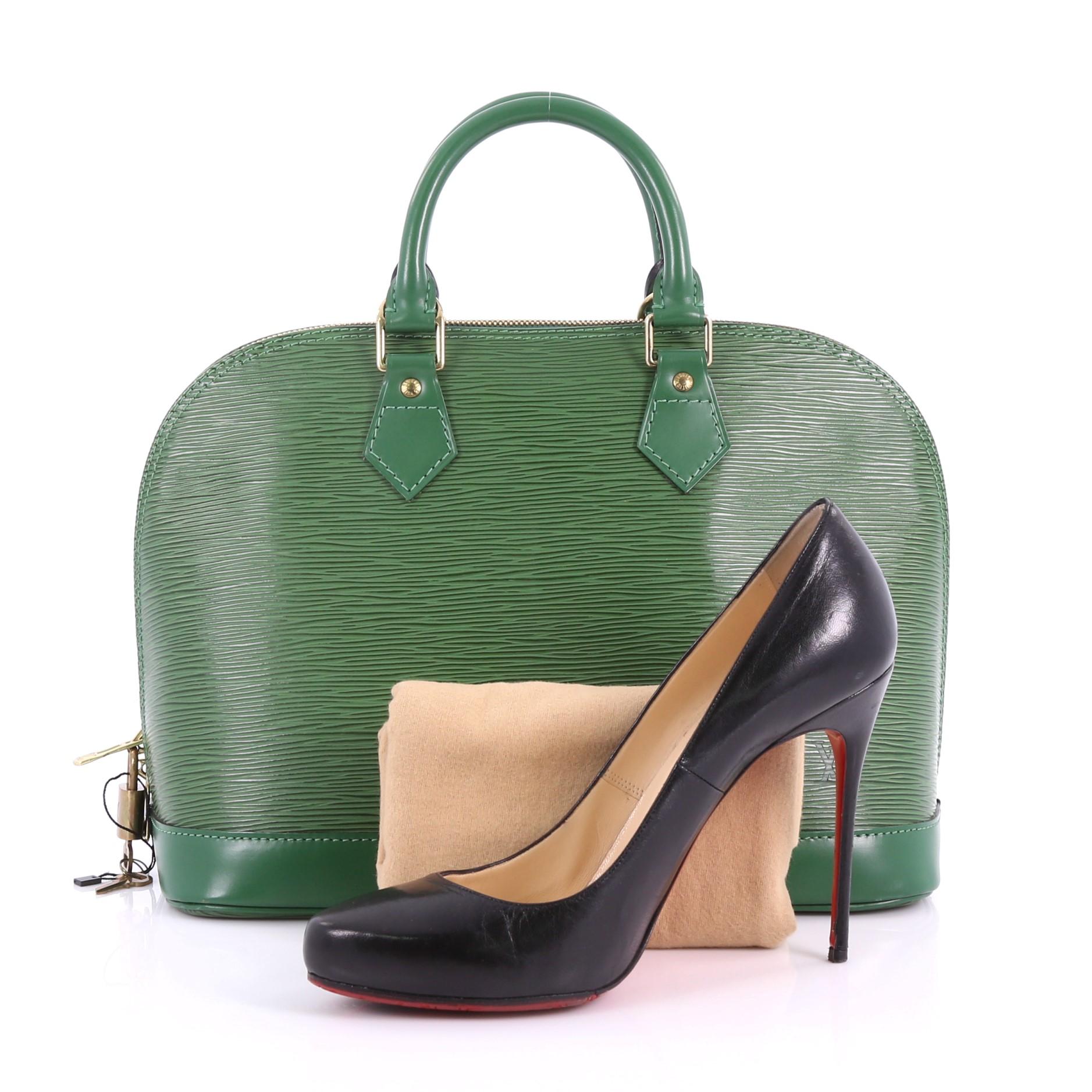 This Louis Vuitton Vintage Alma Handbag Epi Leather PM, crafted from green epi leather, features dual rolled handles, a sturdy reinforced base, and gold-tone hardware. Its all-around zip closure opens to a green microfiber with slip pocket.
