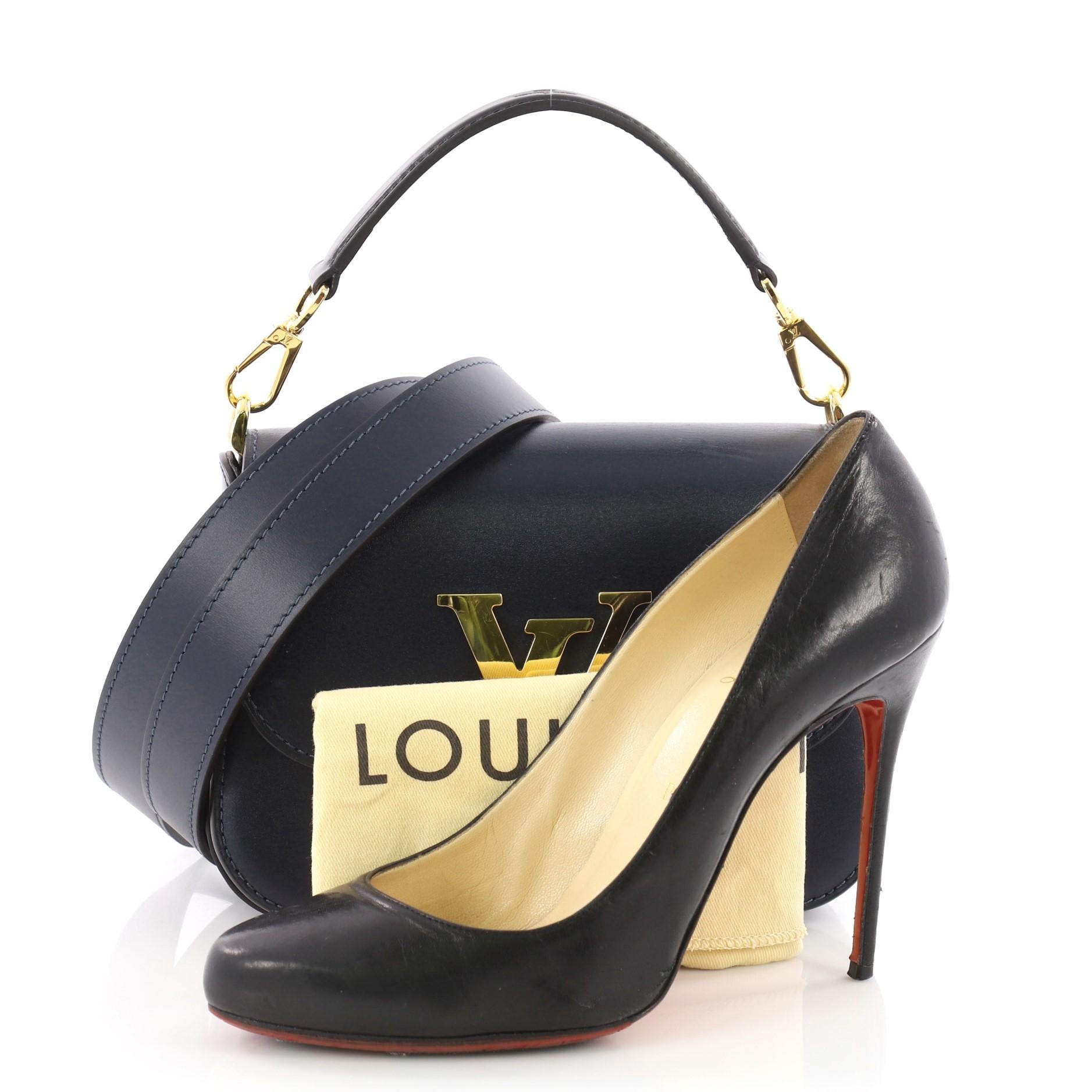 This Louis Vuitton Vivienne LV Bag Box Leather, crafted from navy blue and black leather,  features a leather top handle, frontal lock with prominent LV signature and gold-tone hardware accents. It opens to a black leather interior divided into two