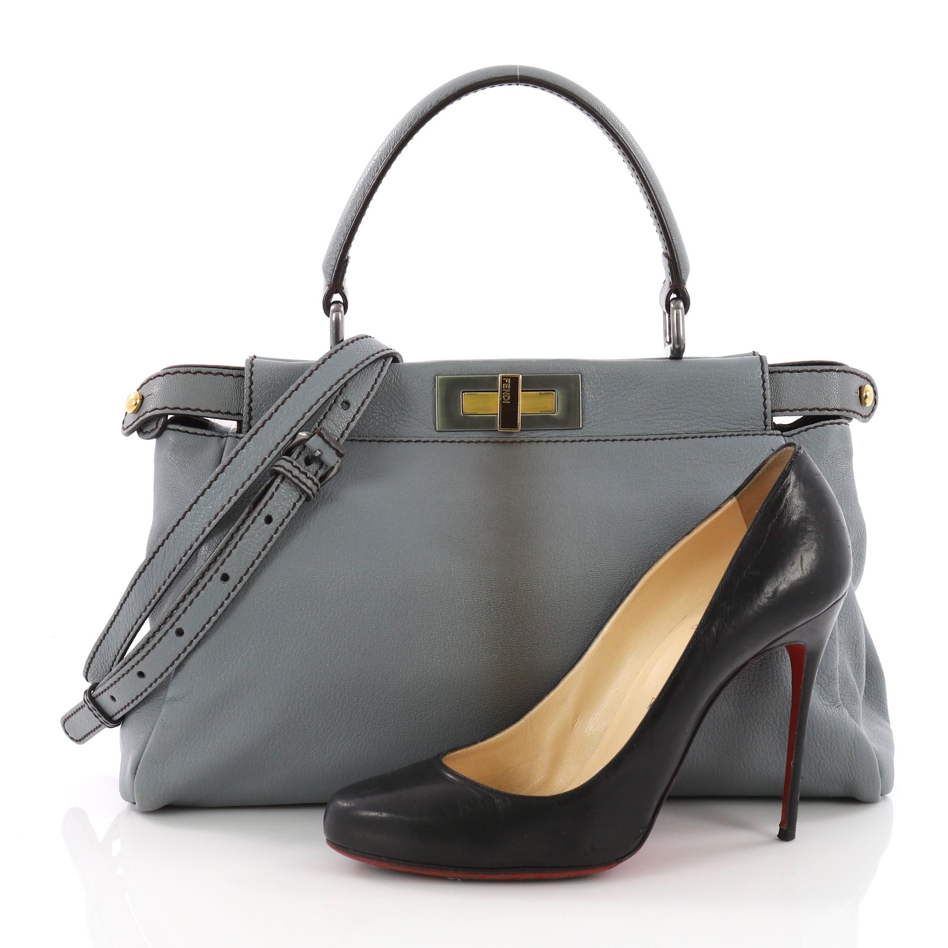 This Fendi Peekaboo Handbag Ombre Leather Regular, crafted from grey leather, features a short leather top handle, frame top, and matte silver and gold hardware. Its two compartments with press-lock and zip closures opens to a brown coated canvas