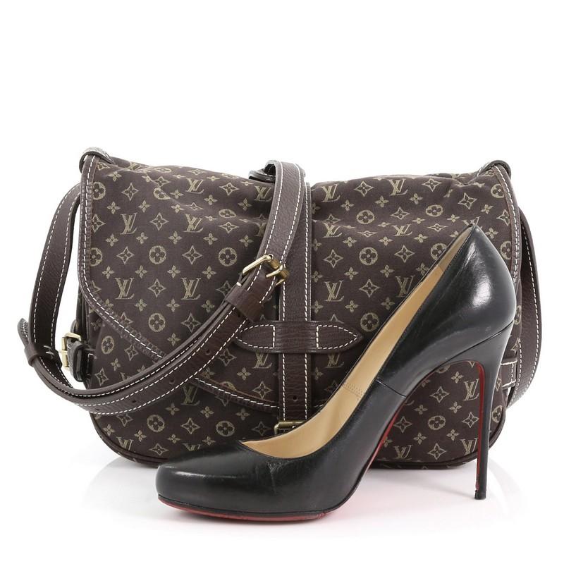 This Louis Vuitton Saumur Handbag Mini Lin, crafted in brown mini lin monogram canvas, features an adjustable leather crossbody strap, brown leather trims and gold-tone hardware. Its buckle closure opens to brown fabric interior with slip