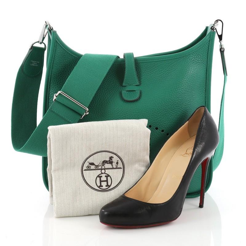 This Hermes Evelyne Crossbody Gen III Clemence PM, crafted from green Vert Vertigo clemence leather, features a perforated H design at the front, adjustable textile shoulder strap and palladium-tone hardware. It opens to a green raw leather