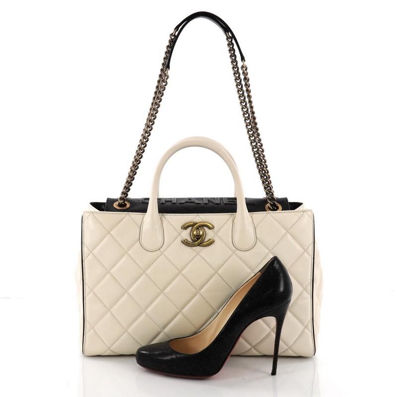 This Chanel Portobello Logo Tote Quilted Lambskin Large, crafted in cream quilted lambskin leather, features dual rolled leather handles, chain-link straps with leather pads, and aged gold-tone hardware. Its turn-lock closure opens to a gold leather
