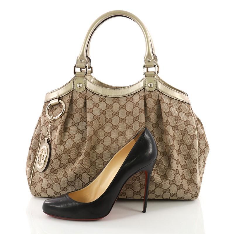 This Gucci Sukey Tote GG Canvas Medium, crafted from brown GG canvas, features dual rolled leather handles, a ruched silhouette, and gold-tone hardware. Its side snap and magnetic snap closures open to a beige fabric interior with side zip pocket.