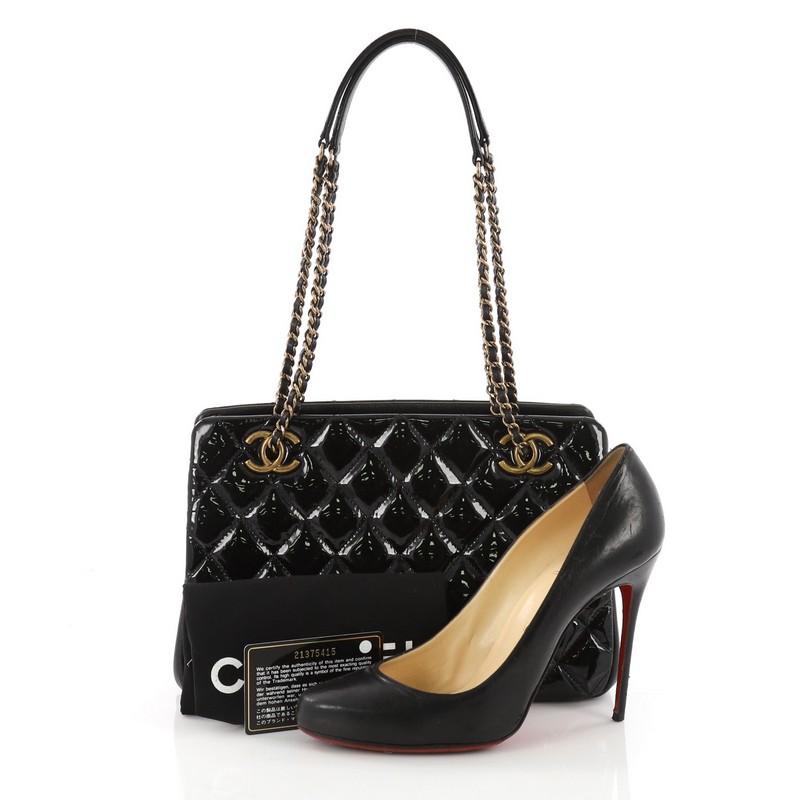 This Chanel Eyelet Tote Quilted Patent Small, crafted in black quilted patent leather, features dual woven in chain straps, protective base studs and aged gold-tone hardware. It opens to a burgundy fabric interior with a middle zip compartment.