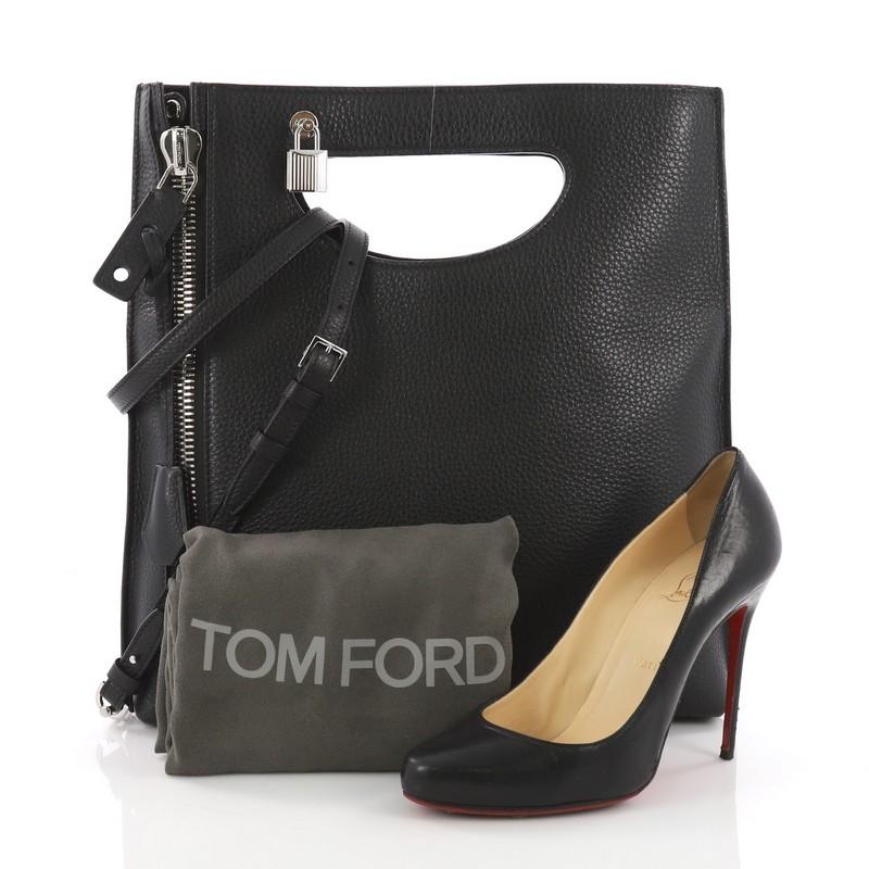 This Tom Ford Alix Fold Over Crossbody Bag Leather, crafted from black leather, features a cutout top handle, exterior back zip pocket, vertical front zip, and silver-tone hardware. Its fold-over top opens to a black microfiber interior with a side