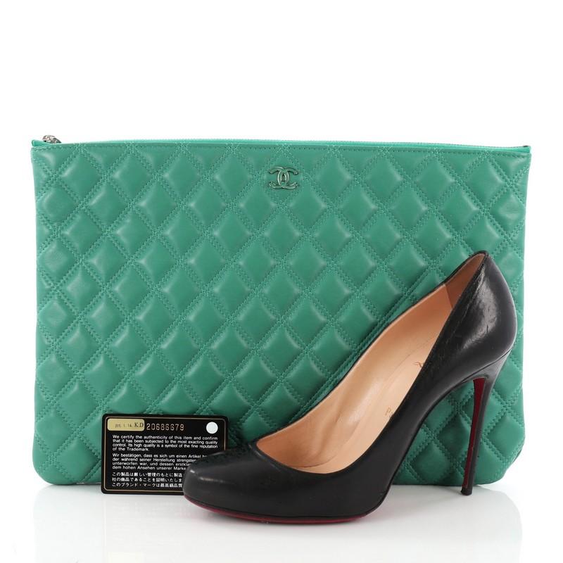 This Chanel O Case Clutch Quilted Lambskin Large, crafted from green quilted lambskin, features a tiny CC logo on the front and silver-tone hardware. Its zip closure opens to a green nylon interior. Hologram sticker reads: 20686679. **Note: Shoe