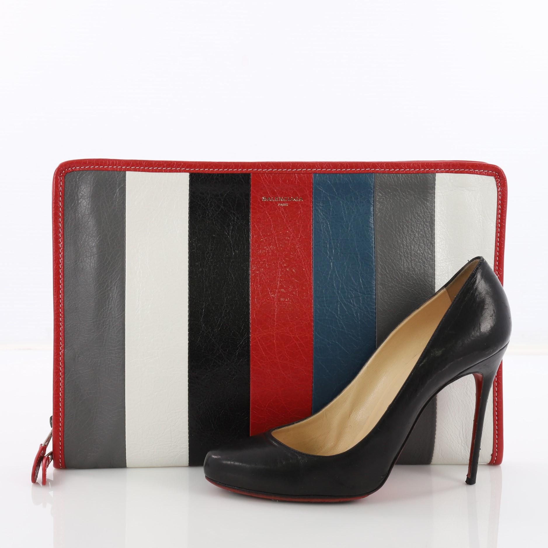 This Balenciaga Bazar Pouch Striped Leather, crafted from red multicolor striped leather, features red leather trimsa nd silver-tone hardware. Its zip closure opens to a black fabric interior with slip pocket. **Note: Shoe photographed is used as a