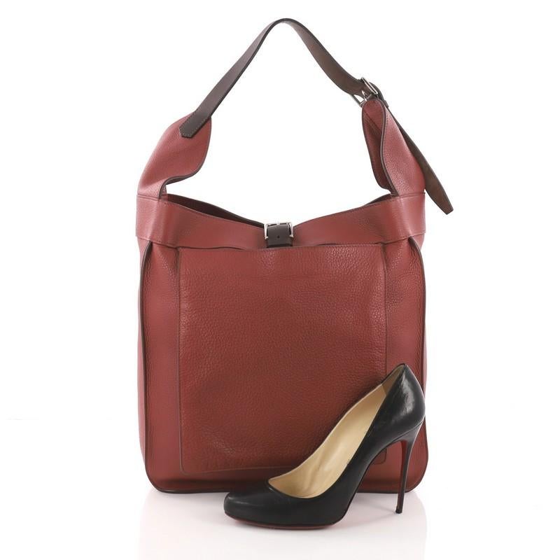 This Hermes Marwari Handbag Clemence GM, crafted from rouge venetian clemence and ebene vache hunter leather, features an adjustable shoulder strap, exterior front slip pocket, and palladium-tone hardware. Its buckle strap opens to a red fabric