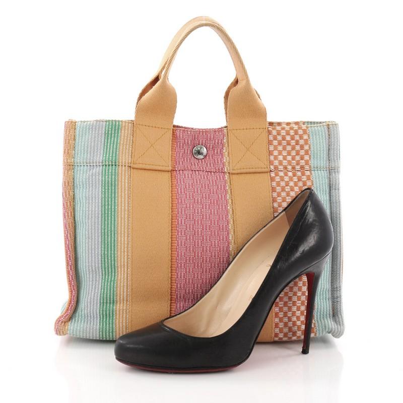 This Hermes Fourre Tout Handbag Multicolor Toile PM, crafted in multicolor toile, features dual top handles and silver-tone hardware accents. Its snap closure opens to a mustard fabric interior. **Note: Shoe photographed is used as a sizing