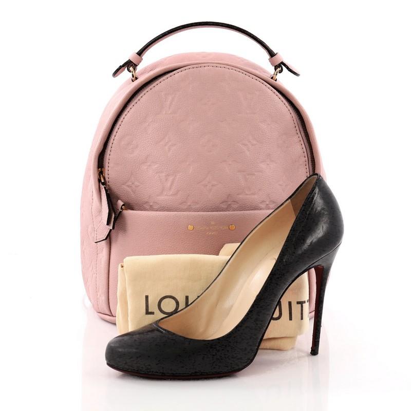 This Louis Vuitton Sorbonne Backpack Monogram Empreinte Leather, crafted in pink monogram empreinte leather, features leather top handle, adjustable shoulder straps, exterior front zip pocket, and gold-tone hardware. Its zip closure opens to a pink