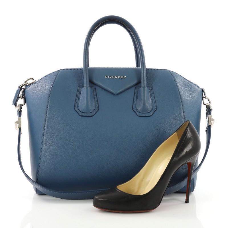 This Givenchy Antigona Bag Leather Medium, crafted from blue leather, features dual rolled leather handles and silver-tone hardware. Its zip closure opens to a beige fabric interior with zip and slip pockets. **Note: Shoe photographed is used as a