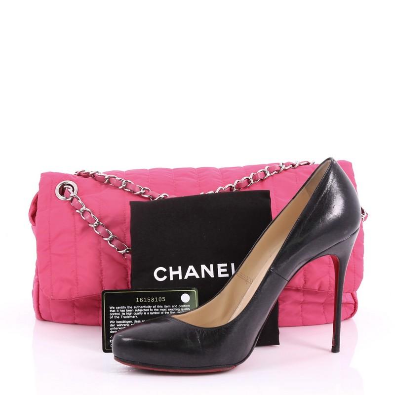 This Chanel Soft Shell Flap Bag Vertical Quilted Nylon Jumbo, crafted from pink quilted nylon, features woven-in leather chain strap, front flap with CC turn-lock closure and silver-tone hardware. Its turn-lock and zip closure opens to a pink
