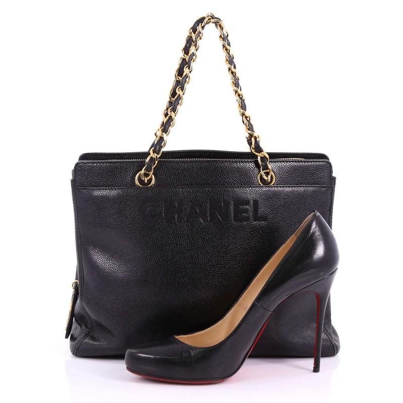 This Chanel Vintage Logo Chain Tote Caviar Medium, crafted in black caviar leather, features dual woven-in leather straps, exterior front pocket, Chanel stitched logo and gold-tone hardware. Its top zip closure opens to a black fabric interior with