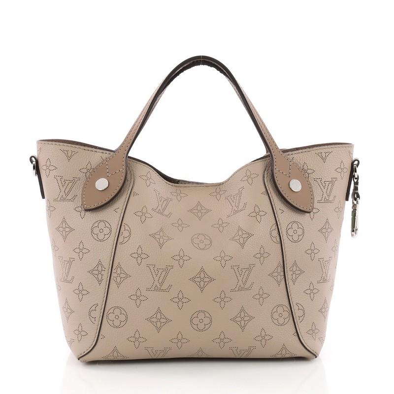 This Louis Vuitton Hina Handbag Mahina Leather PM, crafted from taupe mahina leather, features dual slim leather handles, and silver-tone hardware. Its magnetic snap button closure opens to a taupe microfiber interior. Authenticity code reads: